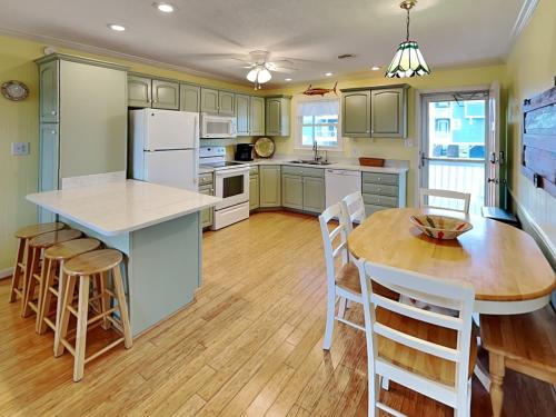 a kitchen with green cabinets and a table and chairs at On Island Time in Topsail Beach