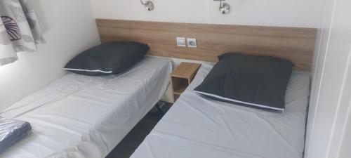 Cette petite chambre comprend deux lits et un oreiller. dans l'établissement Camping les Salins de la Gardiole, à Vic-la-Gardiole