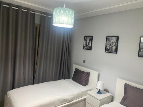 a bedroom with two beds and a chandelier at Marina Saidia Luxury Apartment with Pool & Garden View,Residence Tamaris in Saidia 