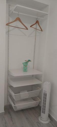uma prateleira branca num quarto com uma lata de lixo em SuecaRoom em Sueca