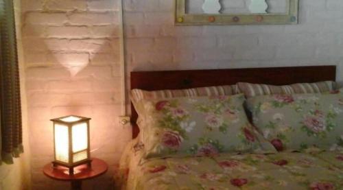 a bedroom with a bed with a lamp on a table at POUSADA SERRANO in São Bento do Sapucaí