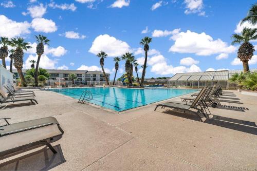 a large swimming pool with chairs and palm trees at Modern Resort Condo - Pools, Courts & Scenic Views in St. George