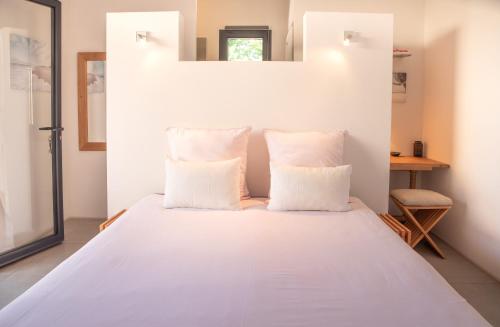 Schlafzimmer mit einem Bett mit weißer Bettwäsche und Kissen in der Unterkunft La Maison du Cotton- Gite bio-climatique in Andernos-les-Bains