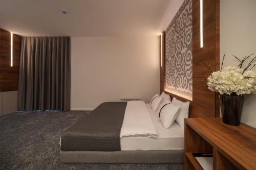 a hotel room with a bed and a vase of flowers at Duo Hotel by Futuro in Bishkek