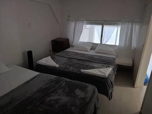 zwei Betten in einem kleinen Zimmer mit Fenster in der Unterkunft Tucacas Penthouse w Generator and Water Tank in Tucacas