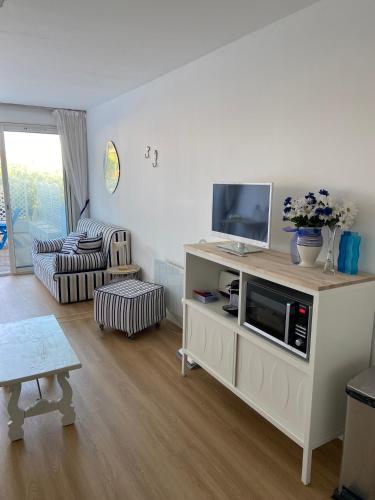 un salon avec une télévision sur une armoire dans l'établissement Studio Le Grau du Roi - proche de la mer, au Grau-du-Roi