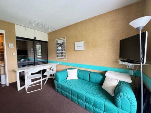 un salon avec un canapé vert et une télévision dans l'établissement Charmant petit Appart au pieds des pistes pour 4pers, à Saint-Étienne-en-Dévoluy