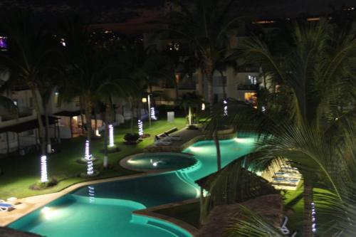 a swimming pool at night with palm trees and lights at Departamento en zona diamante Acapulco in Acapulco