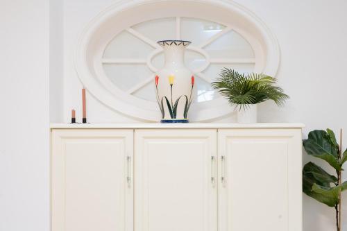 a vase on top of a white cabinet with a mirror at Atik Hotel Vienna in Vienna