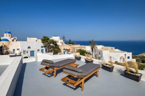 a patio with lounge chairs and the ocean in the background at Aerie 2bedroom by Thireon in Oia