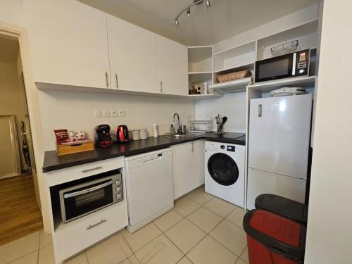une cuisine avec des armoires blanches et une laveuse et une sécheuse dans l'établissement Appartment Garden Plazza jacuzzi privé, à Toulouse