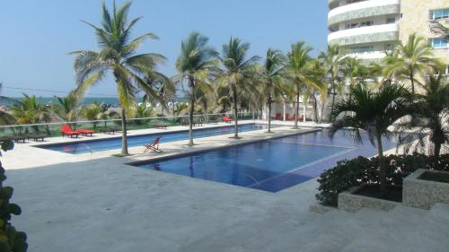 a large swimming pool with palm trees and a building at Apartamento Los Morros in Cartagena de Indias