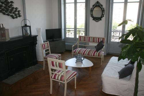 a living room with a couch and chairs and a tv at Chez Mo in Lyon