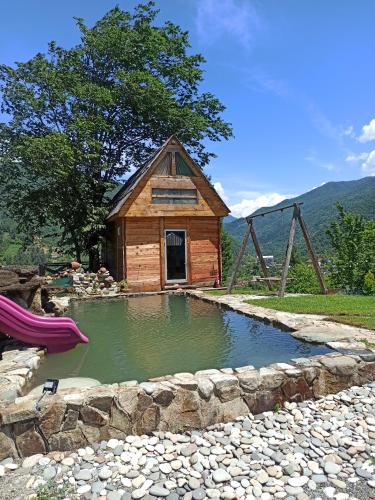 a small house with a pond in front of it at wooden house in Koromkhet'i