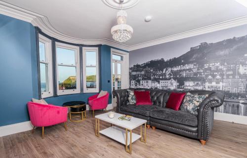 a living room with a black couch and pink chairs at The Boat House Luxury Apartments Scarborough in Scarborough