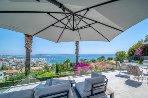 un patio avec une table, des chaises et un parasol dans l'établissement REF 2128 - Cannes - Sea view villa for rent, à Cannes