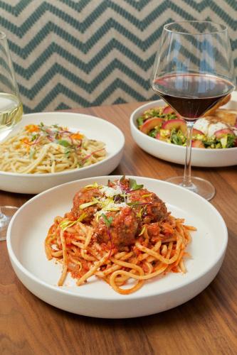 a table with three plates of spaghetti and a glass of wine at River Lodge Paso - 21 & Over Pool in Paso Robles