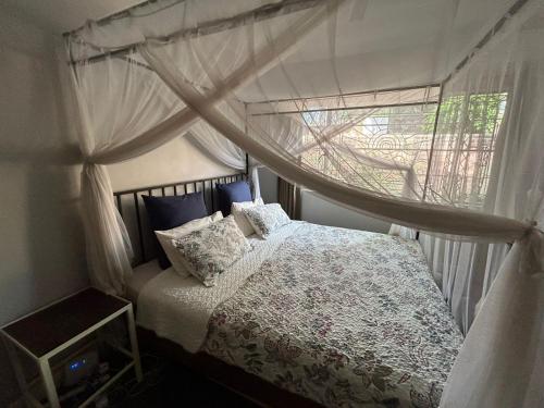Un dormitorio con una cama con dosel y una ventana. en Boma House, en Lilongwe