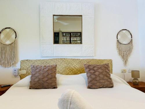 a bedroom with a white bed with two mirrors on the wall at Sirenas Caribbean Rooms Holbox in Holbox Island