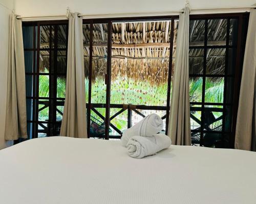 a towel sitting on a bed in front of a window at Sirenas Caribbean Rooms Holbox in Holbox Island