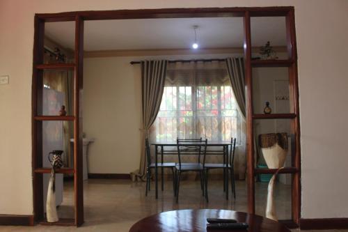 ein Esszimmer mit einem Tisch und einem Fenster in der Unterkunft Montane Safaris Hotel in Fort Portal