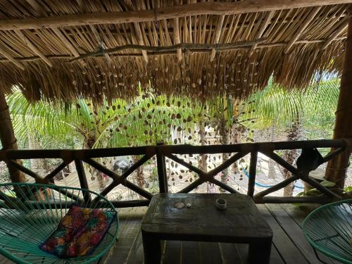 a porch with a chair and a table and a straw roof at Sirenas Caribbean Rooms Holbox in Holbox Island
