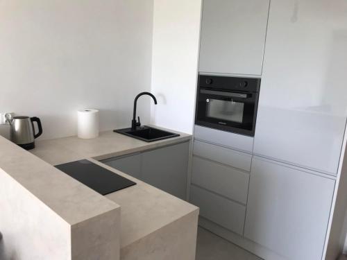 グダニスクにあるApartament Gdańsk 17のシンクとコンロのある白いキッチン