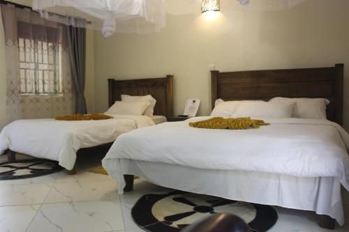 a bedroom with two beds with white comforters at Montane Safaris Hotel in Fort Portal
