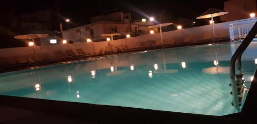 a swimming pool at night with chairs and umbrellas at Dinos Pool Apartment in Kardamaina