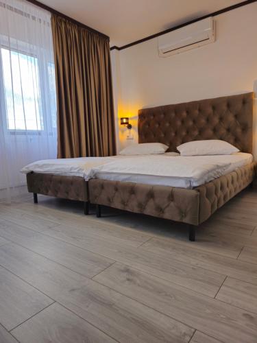 a bedroom with a large bed with a tufted headboard at Pensiunea Minerva in Bistriţa