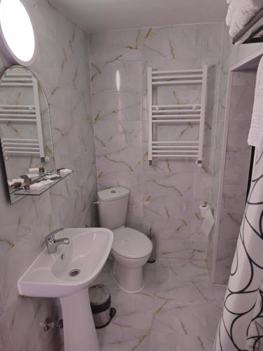 a white bathroom with a toilet and a sink at Pensiunea Minerva in Bistriţa