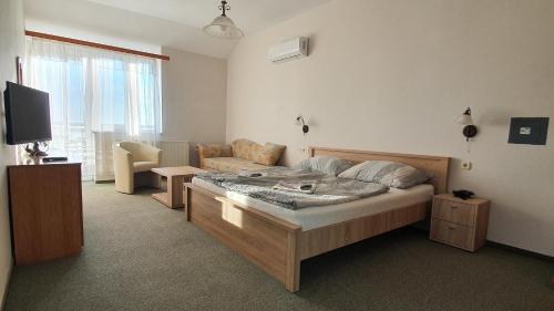 a bedroom with a bed and a couch and a television at Karát Panzió in Balatongyörök