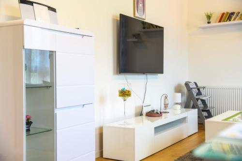 a white living room with a tv on a wall at Apartman ZABOK CENTAR in Zabok