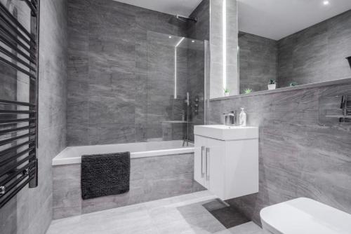 a bathroom with a tub and a sink and a toilet at Maplewood properties - One bedroom luxurious apartment - Elm in St. Albans
