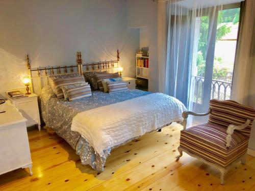 een slaapkamer met een bed, een stoel en een raam bij Casa vacacional La Coruxa in Vidiago