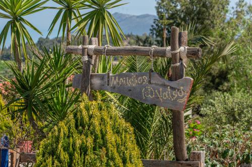 a sign for a garden with palm trees in the background at Moudilos 1 in Lixouri