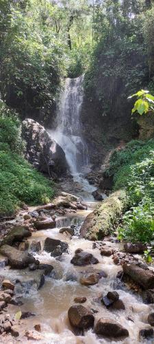 a waterfall on the side of a river with rocks at Hotel Mirador de Quetzales in Providencia