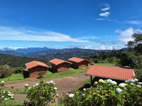 a group of huts in a field with a bench at Hotel Mirador de Quetzales in Providencia