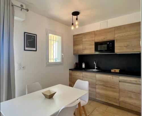 a kitchen with a white table and white chairs at DOMAINE LOU BEL AZUR - Elégant in Saint-Laurent-du-Var