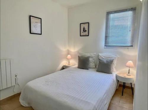 a bedroom with a white bed with two tables and two lamps at DOMAINE LOU BEL AZUR - Elégant in Saint-Laurent-du-Var