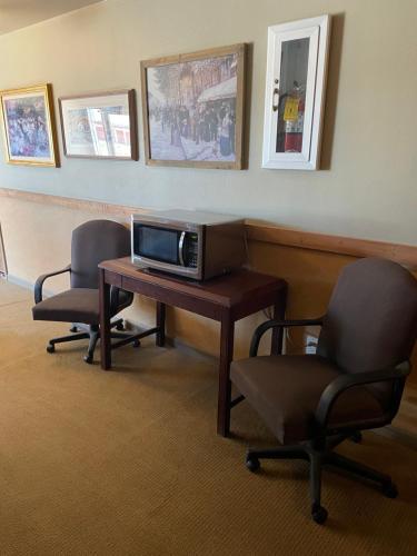 a room with a desk with a tv and two chairs at Rawlins Western Lodge in Rawlins