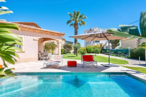 une piscine avec deux chaises et un parasol dans l'établissement Villa Pitou, Piscine chauffée, 200m plage, à La Londe-les-Maures
