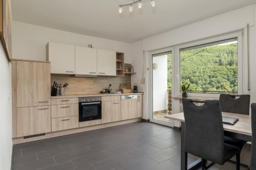 a kitchen with white cabinets and a table and a window at Elbling Appartement for 4 People - Billiards - 2 Bedrooms - 2 Bathrooms - Balcony with Mosel View - Parking - Wine Barrel Bar - Fully Equipped Kitchen - Netflix - WaipuTV - 3 km from Cochem in Klotten