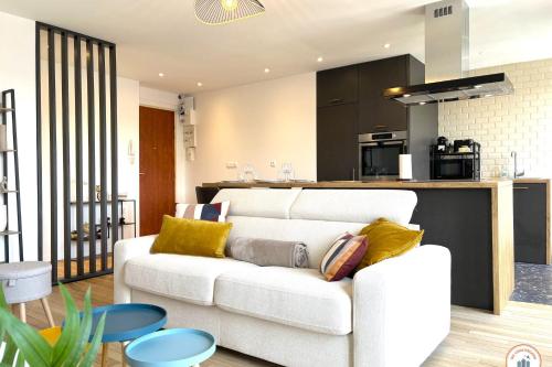 un salon avec un canapé blanc et une cuisine dans l'établissement La Porte de l'Europe - Aperçu mer - Parking, au Havre