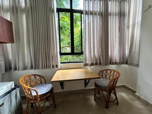 a kitchen with a table and two chairs and a window at 1 BHK Fully Furnished - Soorya Madhavam Apartments - Flat No - C2 - Guruvayur, - 150m to North Nada - Family only in Guruvāyūr