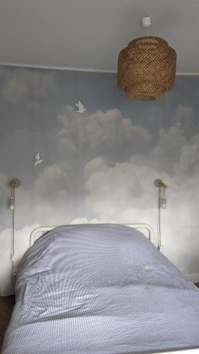 - une chambre avec un lit blanc recouvert de nuages dans l'établissement Agréable maison bord de mer, à Fouras