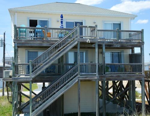 a house with a wooden deck in front of it at Piccolo Paradiso in Topsail Beach