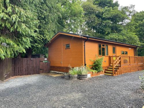 a small wooden cabin with a fence and some plants at Riverbank Lodge in Dollar