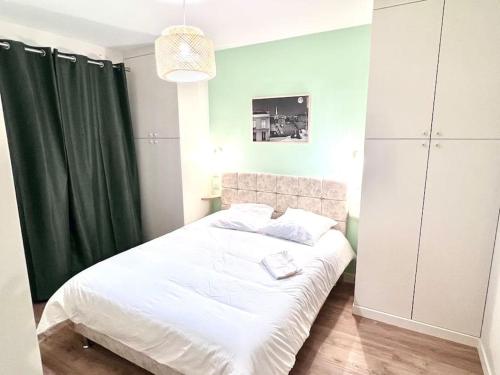 - une chambre avec un lit blanc et un rideau vert dans l'établissement appartment 15 min from paris, à Drancy