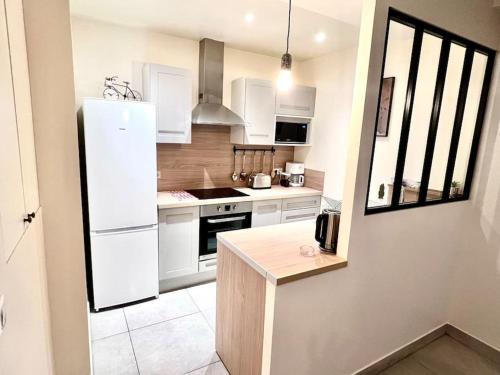 une cuisine avec des armoires blanches et un réfrigérateur blanc dans l'établissement appartment 15 min from paris, à Drancy